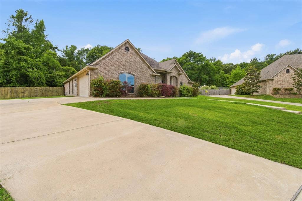 7765 Hickory Spring Lane, Tyler, TX 75703 Brick exterior residence featuring a gabled roofline, an arched window, and an attached two-car garage