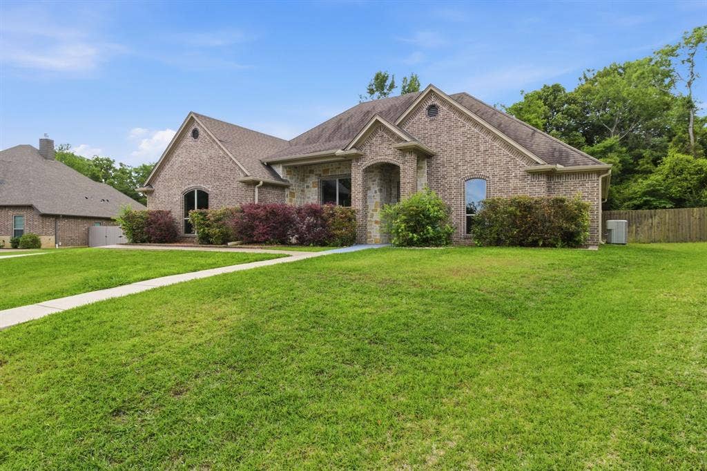 7765 Hickory Spring Lane, Tyler, TX 75703 Brick and stone exterior featuring an arched entry, multiple gables, and a shingle roof