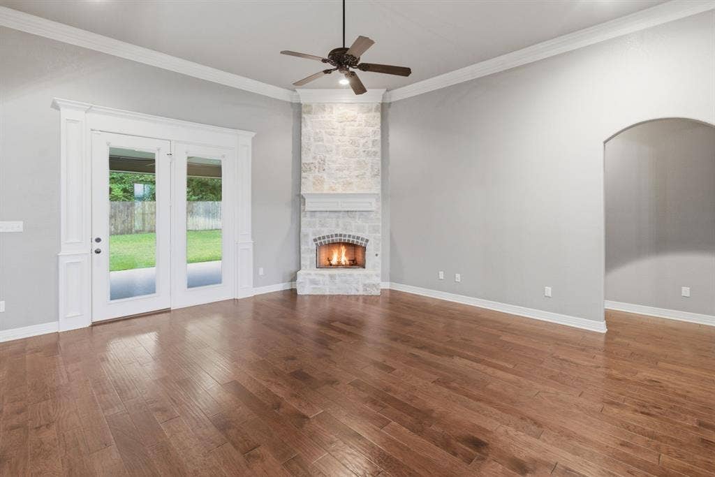 7765 Hickory Spring Lane, Tyler, TX 75703 Living area featuring wood-finish flooring, a stone-clad fireplace with a decorative mantel, and a ceiling fan