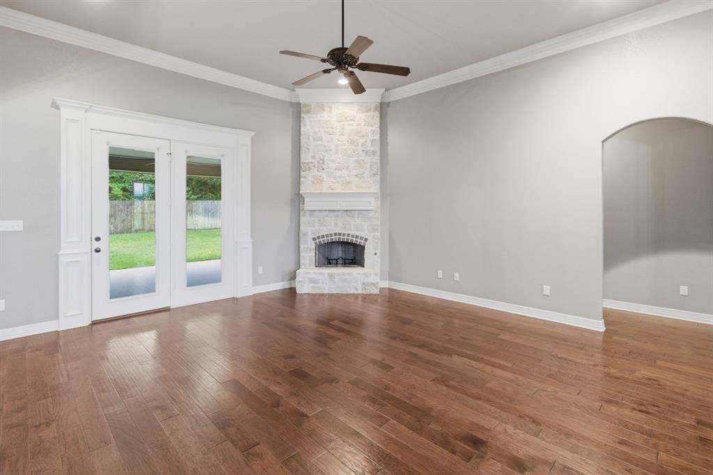 7765 Hickory Spring Lane, Tyler, TX 75703 Spacious living area featuring wood-finish flooring, a stone fireplace with a white mantel, and ceiling fan