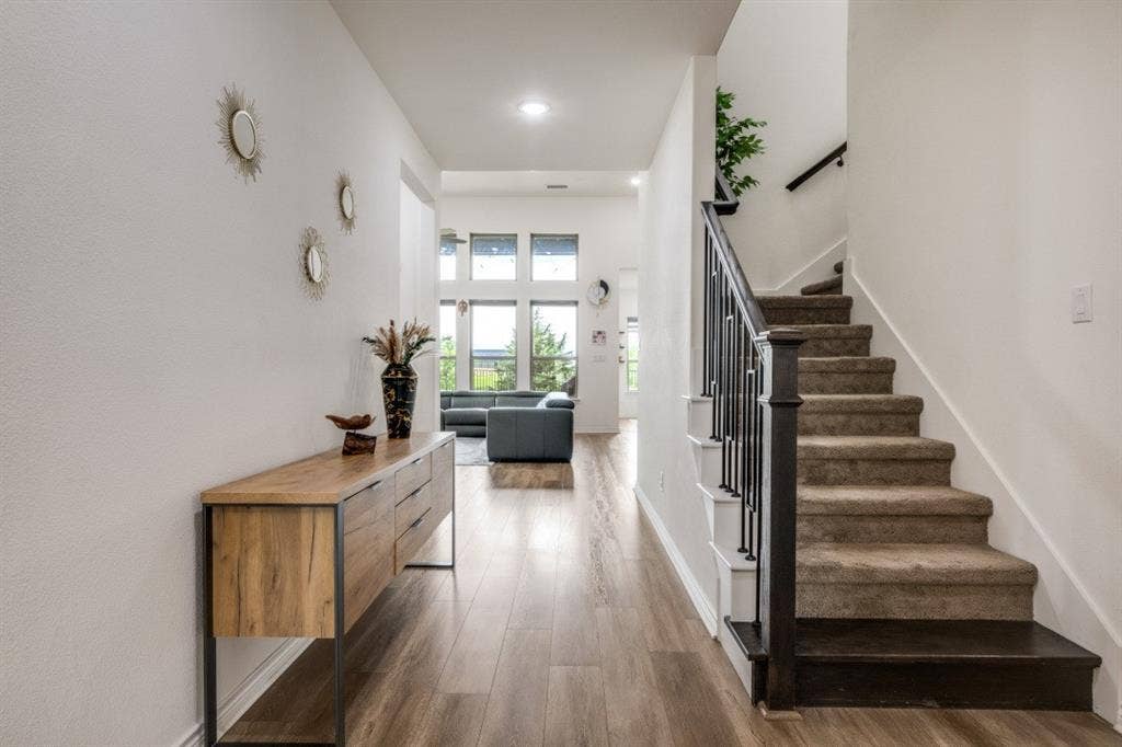 2813 Walker Way, Northlake, TX 76247 Foyer featuring wood-finish flooring extending into the main living space, a carpeted staircase with dark wood newel posts and handrail, and an open concept beyond