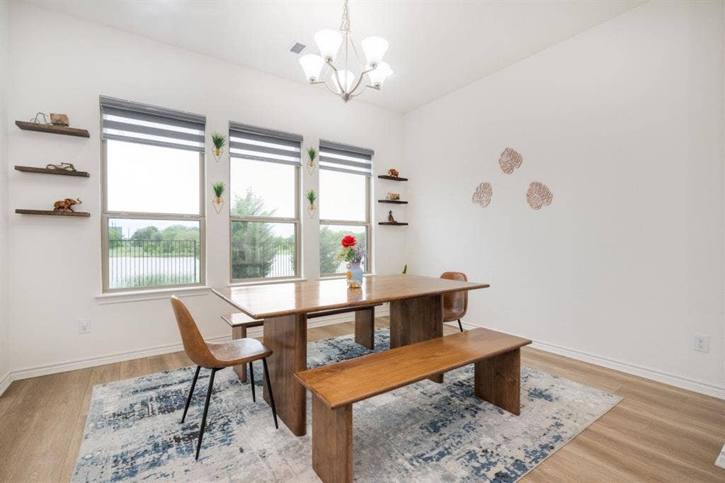 2813 Walker Way, Northlake, TX 76247 Dining area featuring abundant natural light from three windows, wood-finish flooring, a contemporary chandelier, and built-in floating shelves