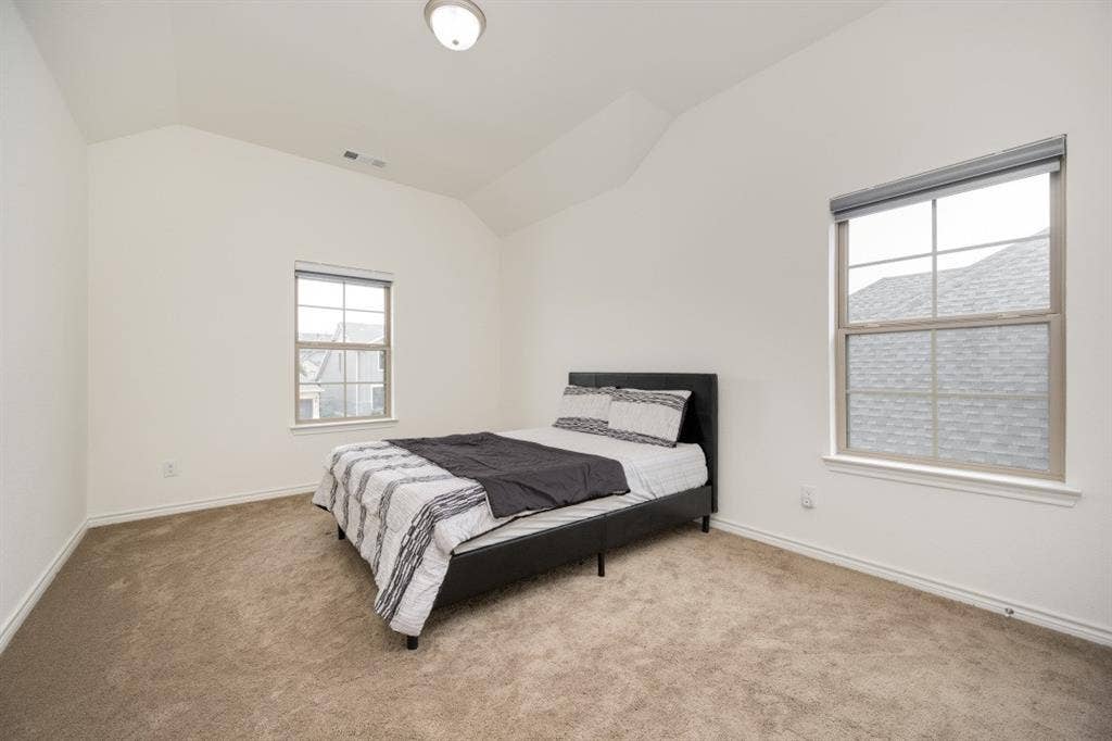 2813 Walker Way, Northlake, TX 76247 Carpeted room featuring a vaulted ceiling, two windows with blinds, and a flush-mount ceiling light fixture