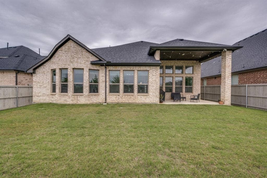 2813 Walker Way, Northlake, TX 76247 Expansive backyard featuring a covered patio with string lighting, a large concrete slab, and a stone-brick exterior