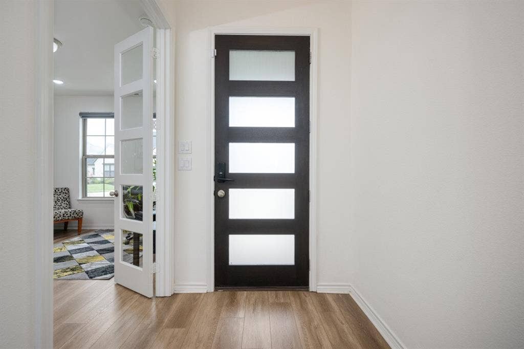 2813 Walker Way, Northlake, TX 76247 Entryway featuring wood-finish flooring, a contemporary dark-paneled door with frosted glass inserts, and a light-colored interior door with clear glass panels