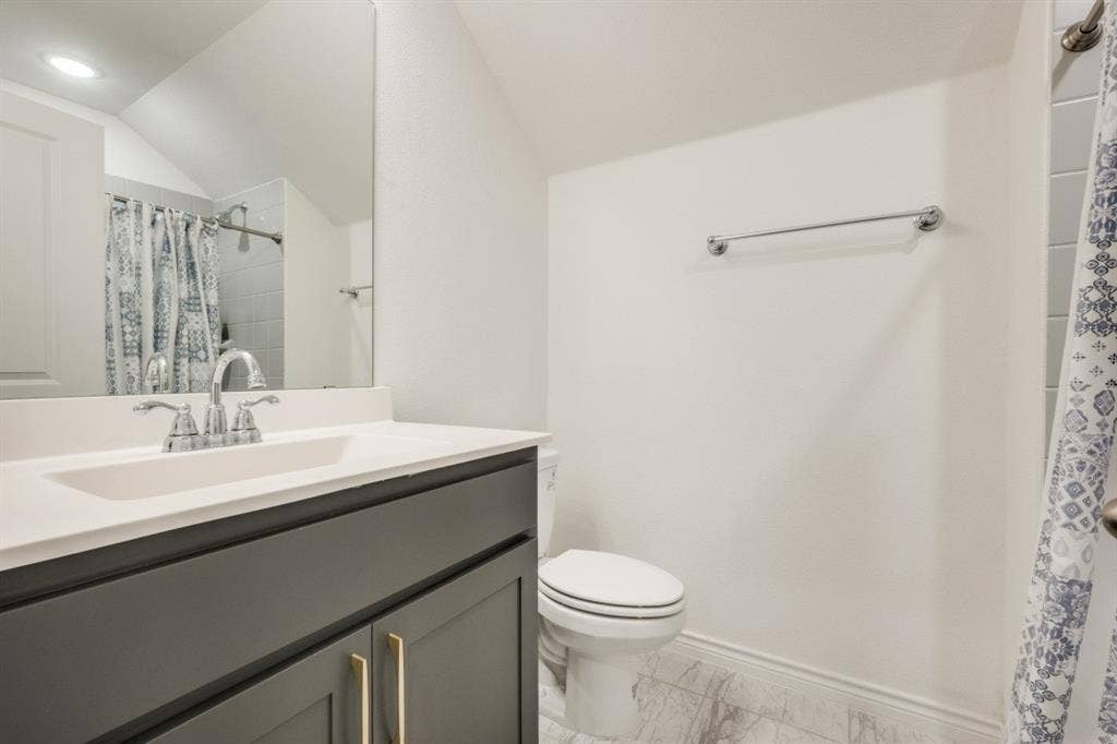 2813 Walker Way, Northlake, TX 76247 Bathroom featuring a vanity with a white countertop, undermount sink, and dark cabinetry with gold-toned hardware