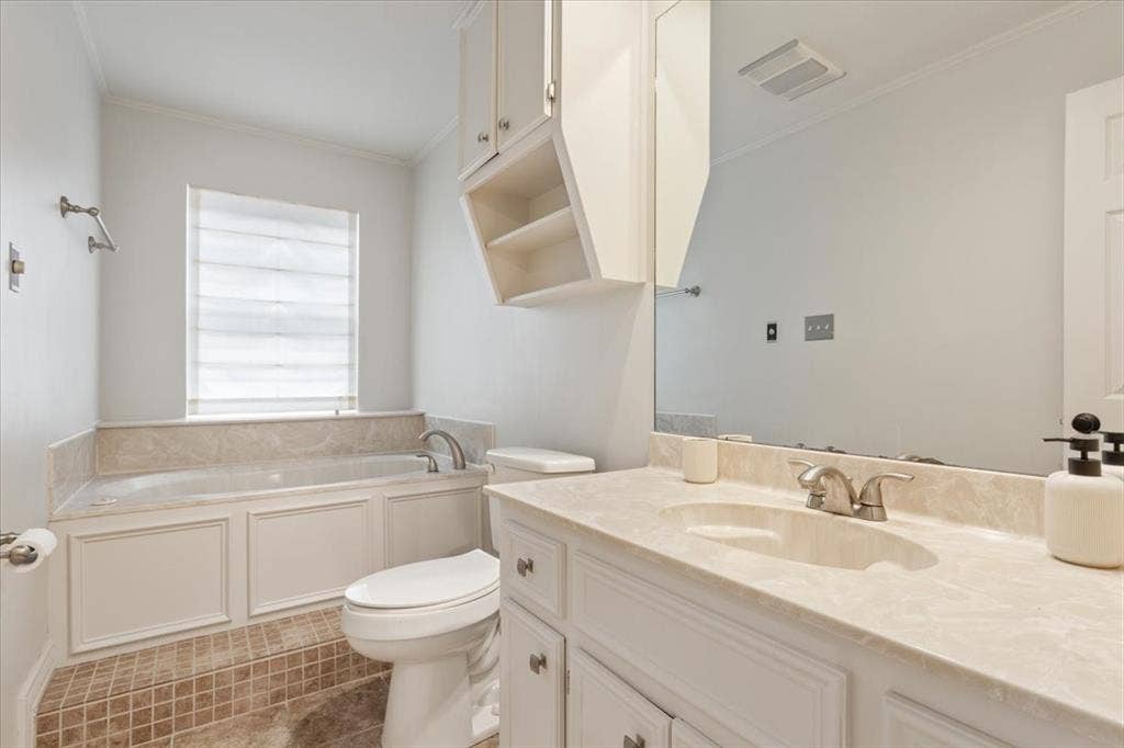 402 Shadow Mountain Drive, Woodway, TX 76712 Bathroom featuring a built-in tub with a stone surround, a single vanity with stone countertop and integrated sink, a large wall-mounted mirror, and white cabinetry