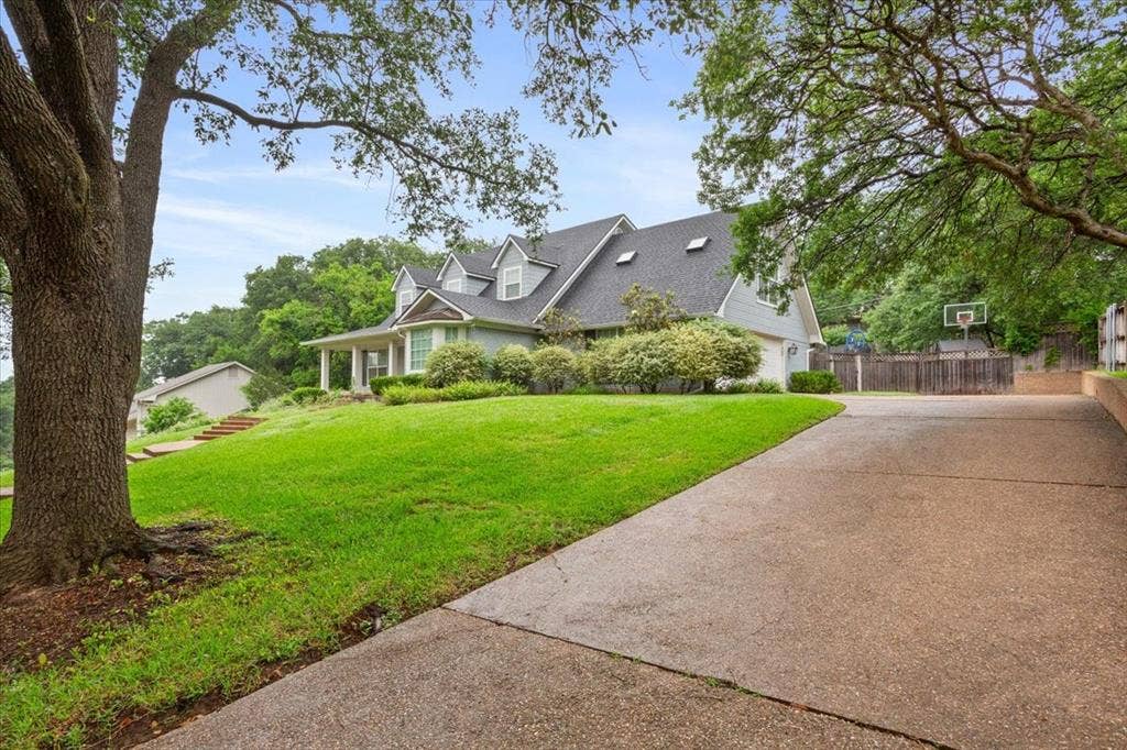 402 Shadow Mountain Drive, Woodway, TX 76712 Traditional-style residence featuring a prominent front porch with columns, dormer windows, and a dark shingle roof