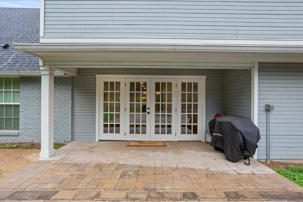 402 Shadow Mountain Drive, Woodway, TX 76712 Paved patio featuring a covered overhang with white support columns, dual French doors with grid-patterned glass, and light blue siding