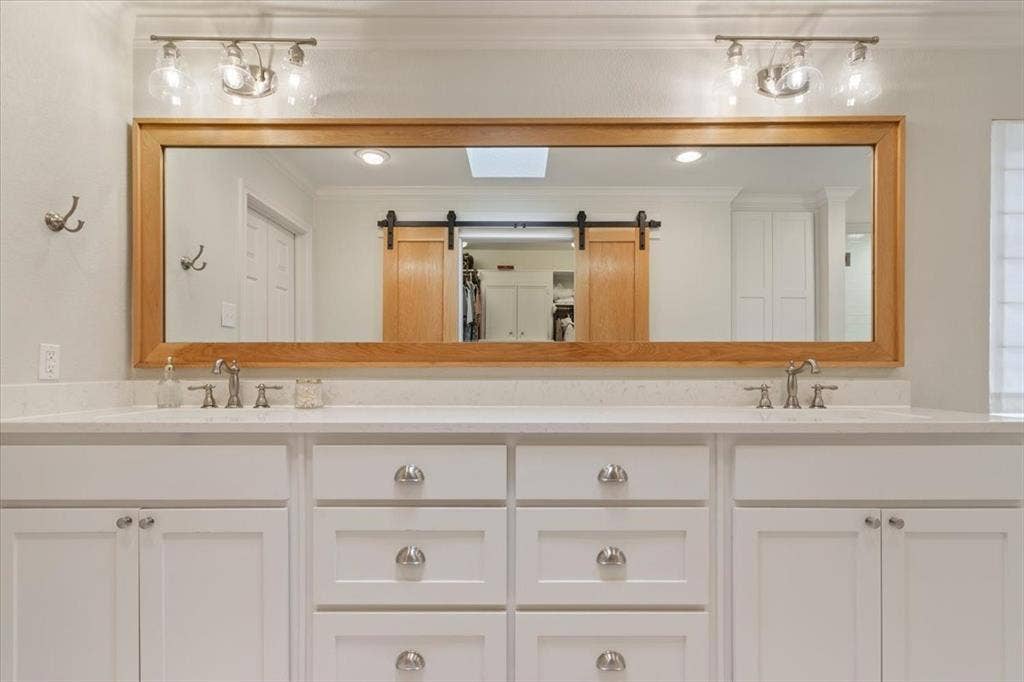 402 Shadow Mountain Drive, Woodway, TX 76712 Upstairs dual vanity with white cabinetry, light-toned countertops, and brushed nickel hardware