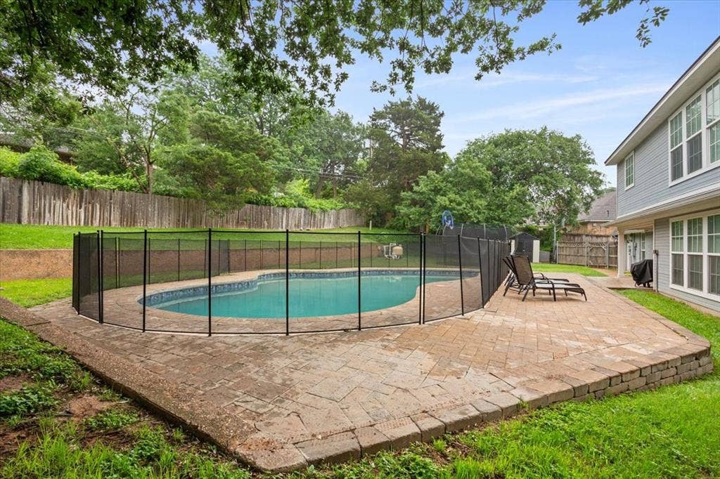 402 Shadow Mountain Drive, Woodway, TX 76712 Backyard swimming pool with a black mesh safety fence, surrounded by a paver patio and mature trees