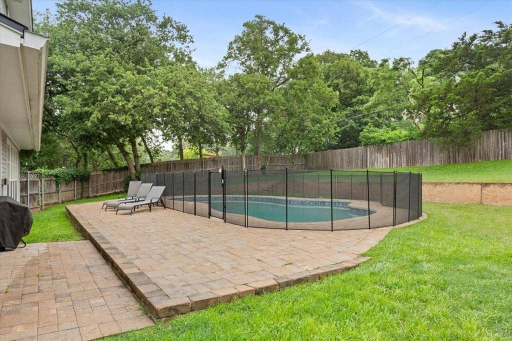 402 Shadow Mountain Drive, Woodway, TX 76712 Backyard featuring a paver patio with a fenced-in swimming pool, surrounded by a grassy lawn and mature trees