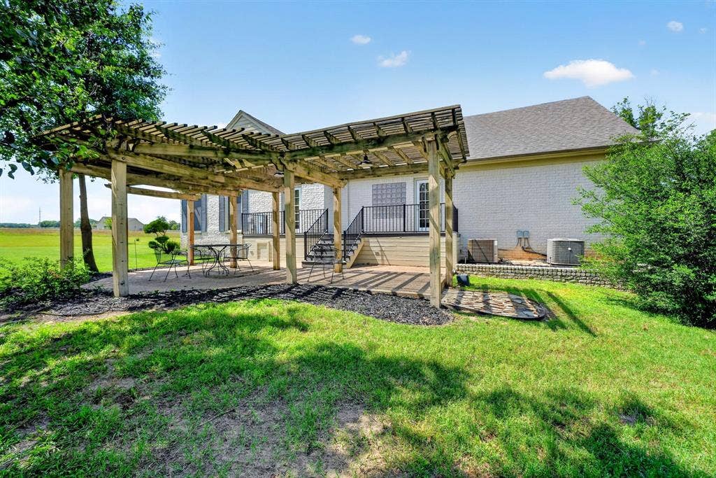 1901 Rose Point, Athens, TX 75752 Expansive outdoor patio featuring a wooden pergola, gravel ground cover, and a staircase leading to an upper-level deck with black railings