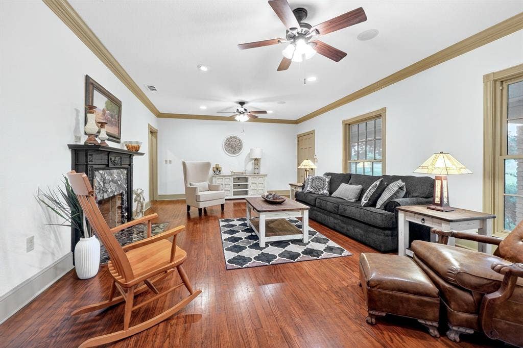 1901 Rose Point, Athens, TX 75752 Spacious living area featuring polished wood-finish flooring, a decorative fireplace with a dark mantel and stone surround, and multiple ceiling fans