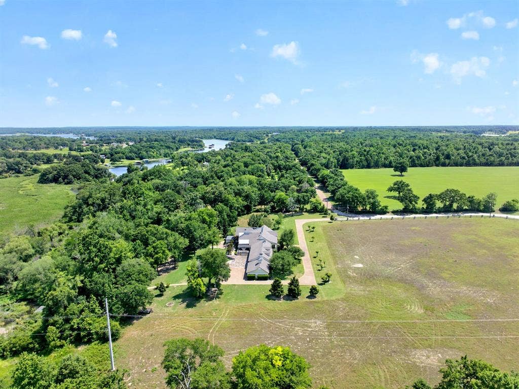 1901 Rose Point, Athens, TX 75752 Spacious property featuring a large residence with an attached garage, extensive surrounding greenery, mature trees, and a distant body of water