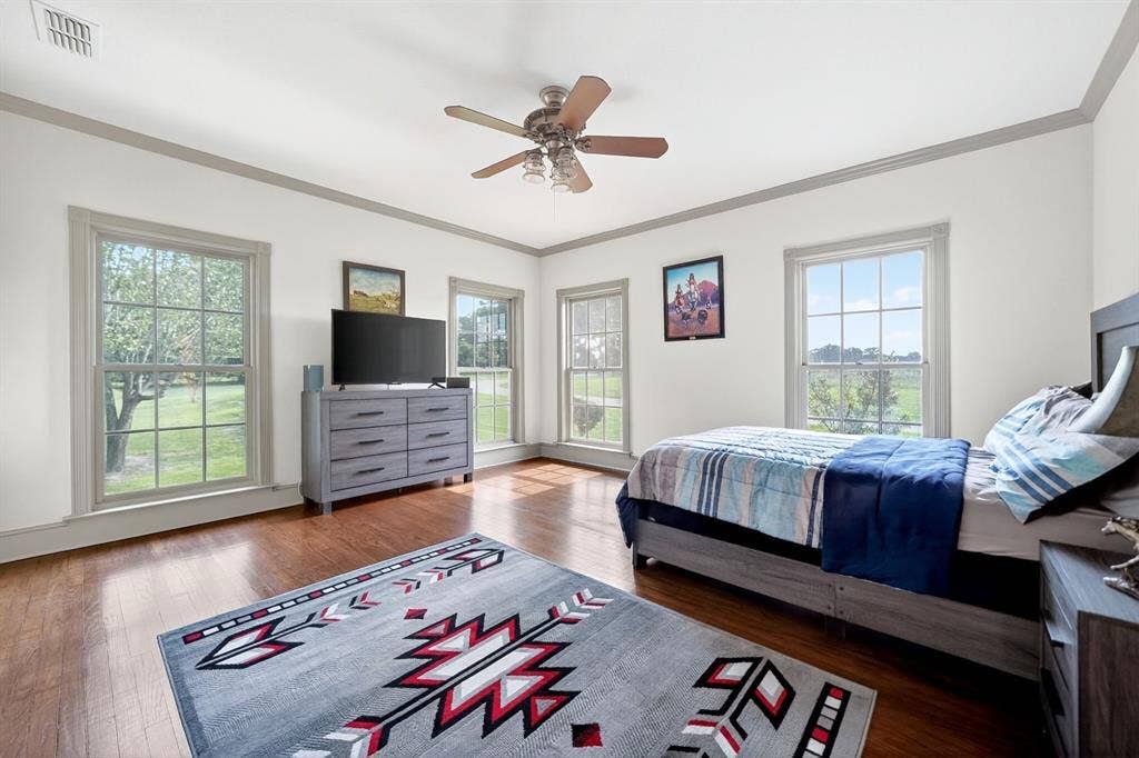 1901 Rose Point, Athens, TX 75752 Spacious room featuring wood-finish flooring, white walls with gray trim, multiple double-hung windows, and a ceiling fan with integrated lighting