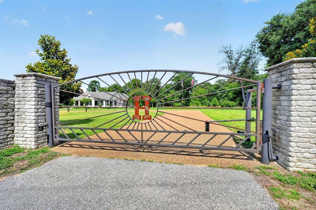 1901 Rose Point, Athens, TX 75752 Automated metal gate with stone-clad pillars, gravel driveway, and expansive manicured lawn