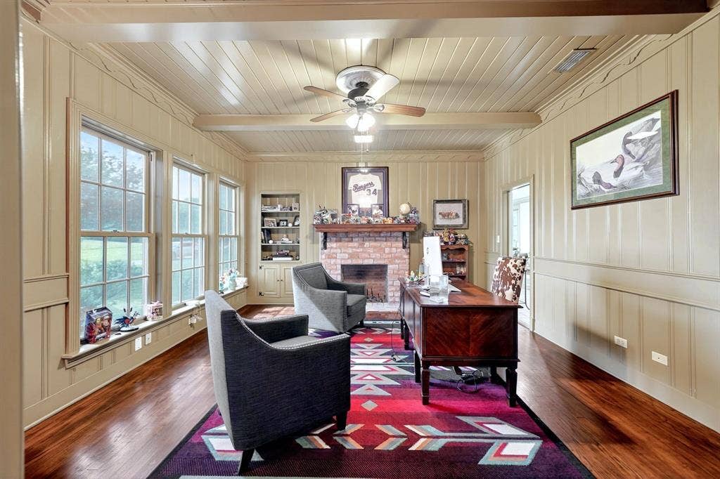 1901 Rose Point, Athens, TX 75752 Room featuring wood-finish flooring, a brick fireplace, built-in shelving, paneled walls, and multiple grid-pattern windows