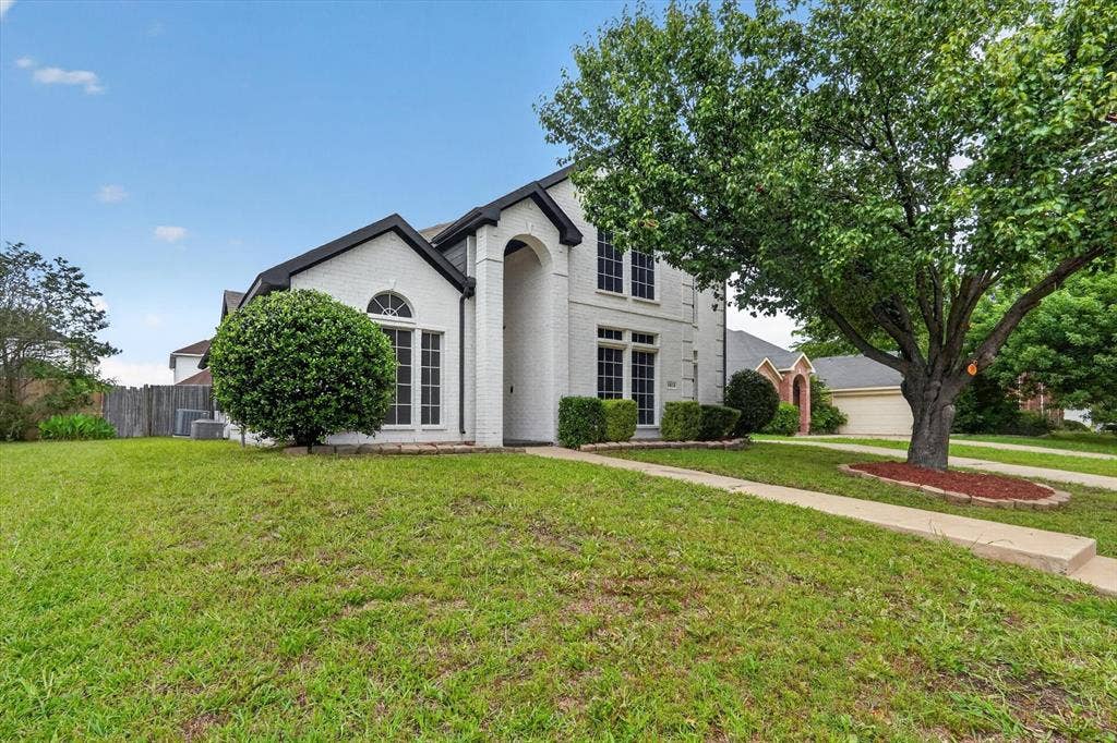 Two-story residence featuring white brick exterior with black trim accents and a prominent arched entryway