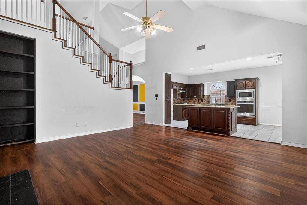 Expansive living area featuring vaulted ceilings, rich wood-finish flooring, and a built-in bookshelf