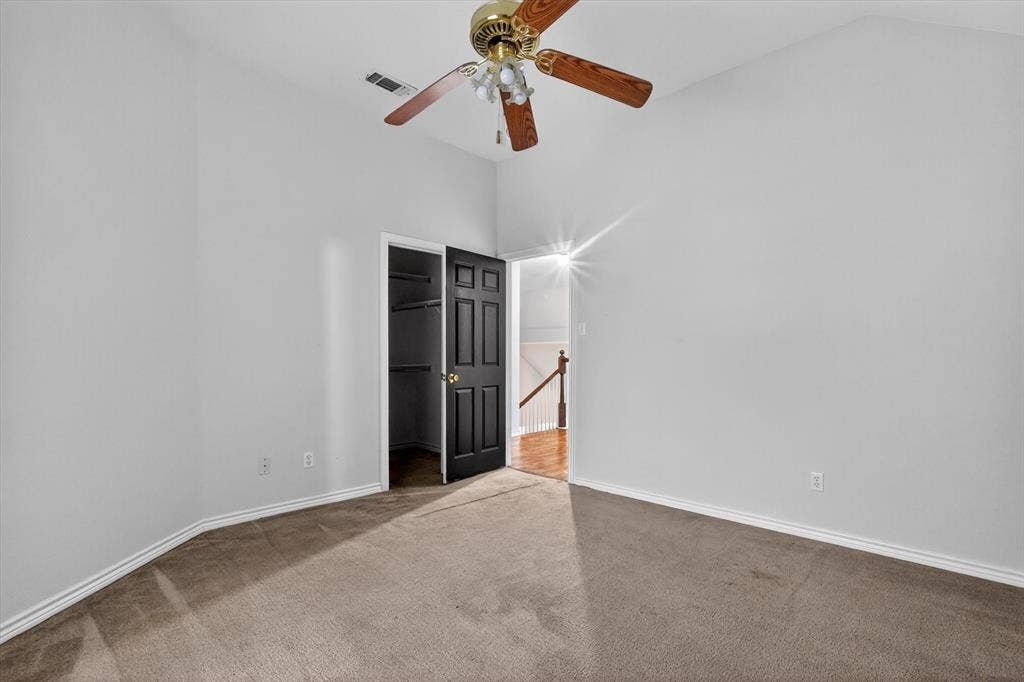 Carpeted room with vaulted ceilings and a ceiling fan