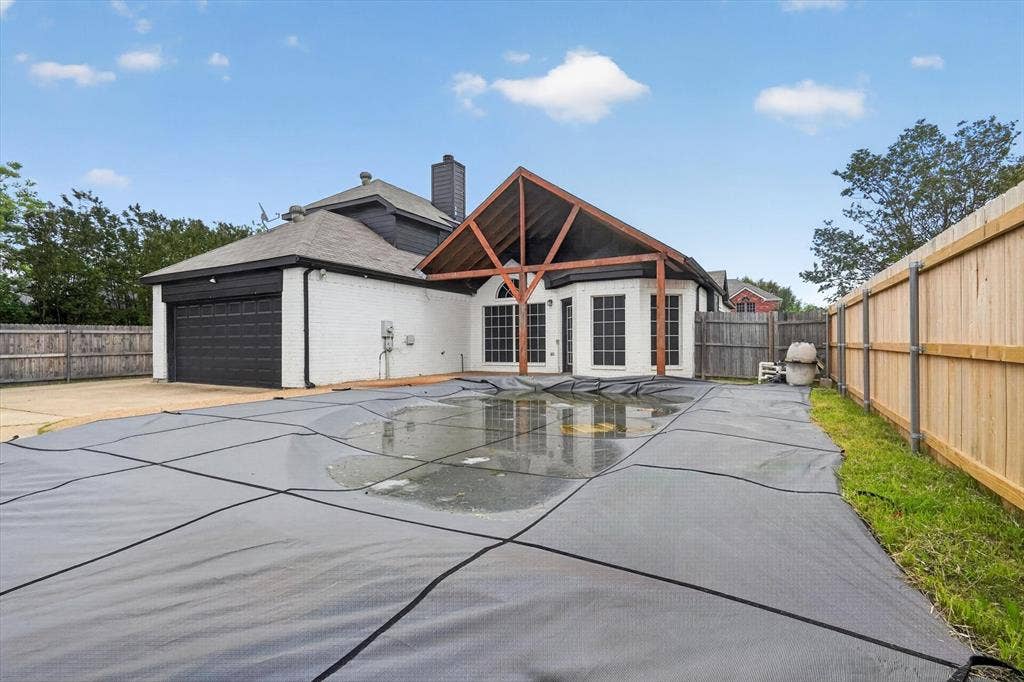 Covered pool area featuring a white brick exterior with dark trim and a prominent wooden patio cover