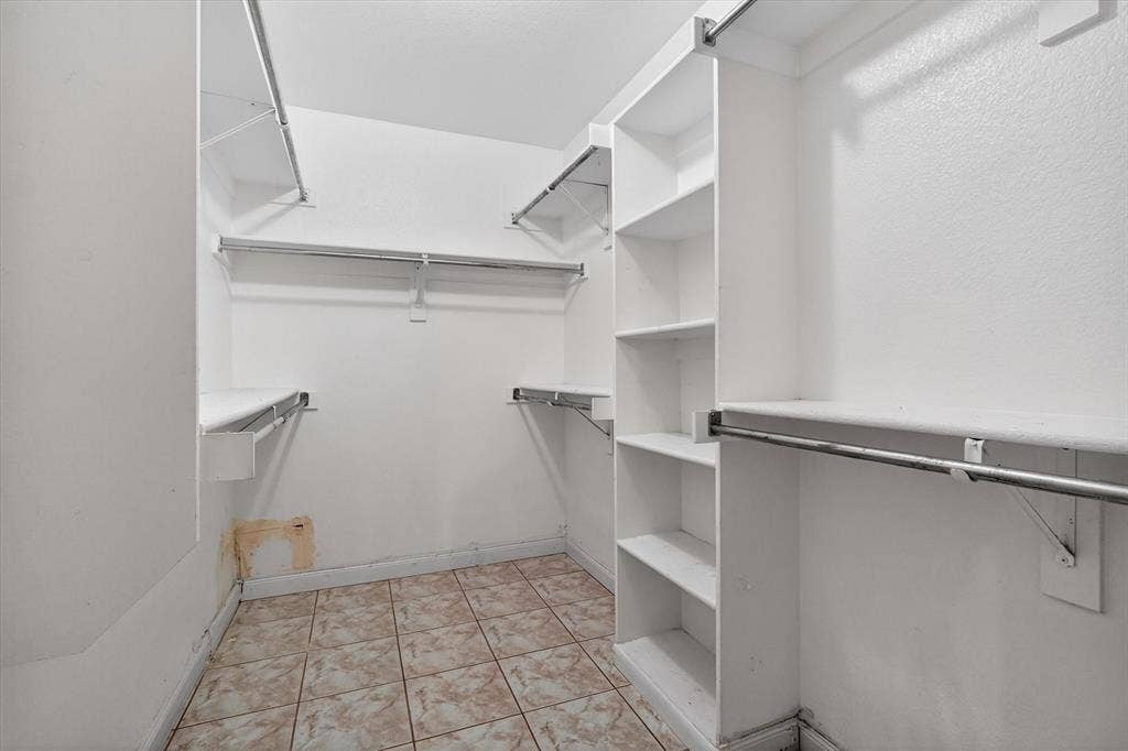 Walk-in closet featuring built-in shelving, hanging rods, and tiled flooring