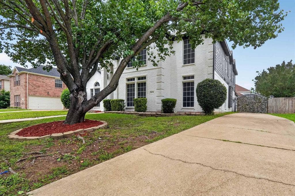 Two-story residence featuring a white brick facade and dark-framed windows