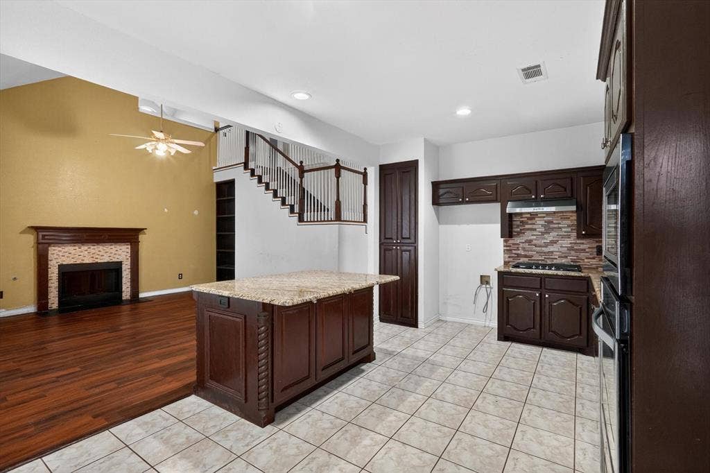 Kitchen with granite-topped island, dark wood cabinetry, and a mosaic tile backsplash