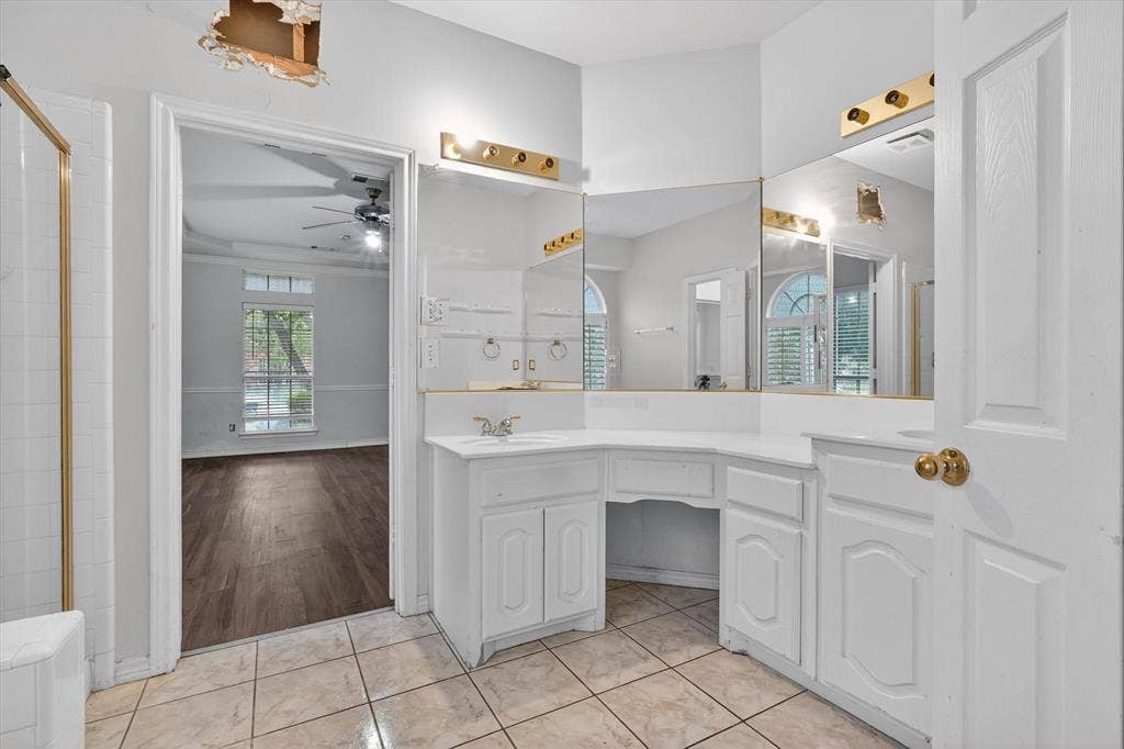 Bathroom vanity with integrated sink, extensive mirror, and overhead lighting