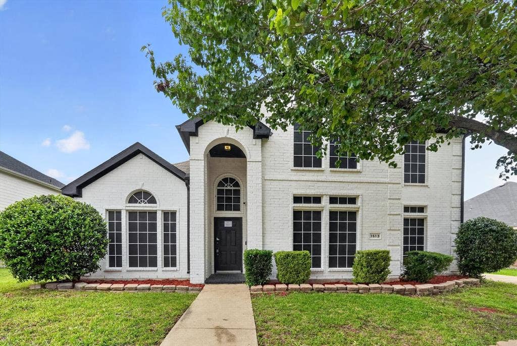 Two-story residence featuring a white brick exterior and a contrasting black roof