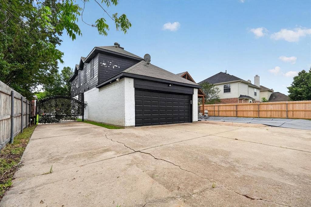 Detached garage with a black panel door, white brick siding, and dark roofing
