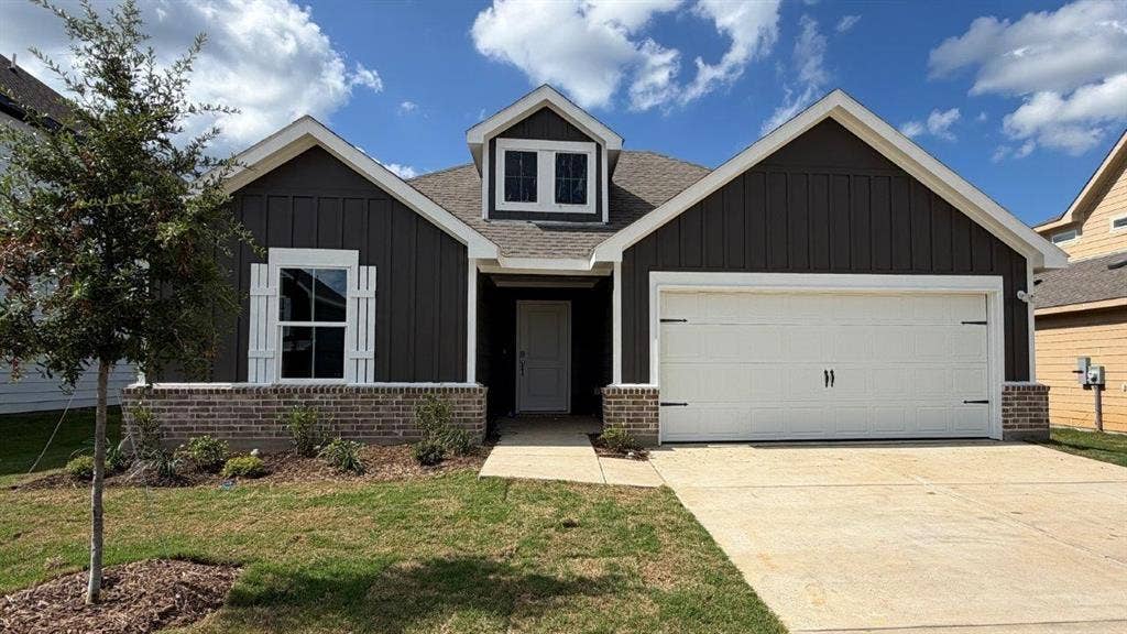 3013 Hidden Valley Drive, Lindale, TX 75771 Cottage-style exterior featuring board and batten siding, a prominent front-facing gable, and a two-car garage with decorative hardware