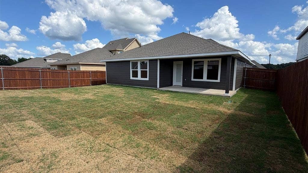 3013 Hidden Valley Drive, Lindale, TX 75771 Rear exterior with dark gray siding and white trim windows