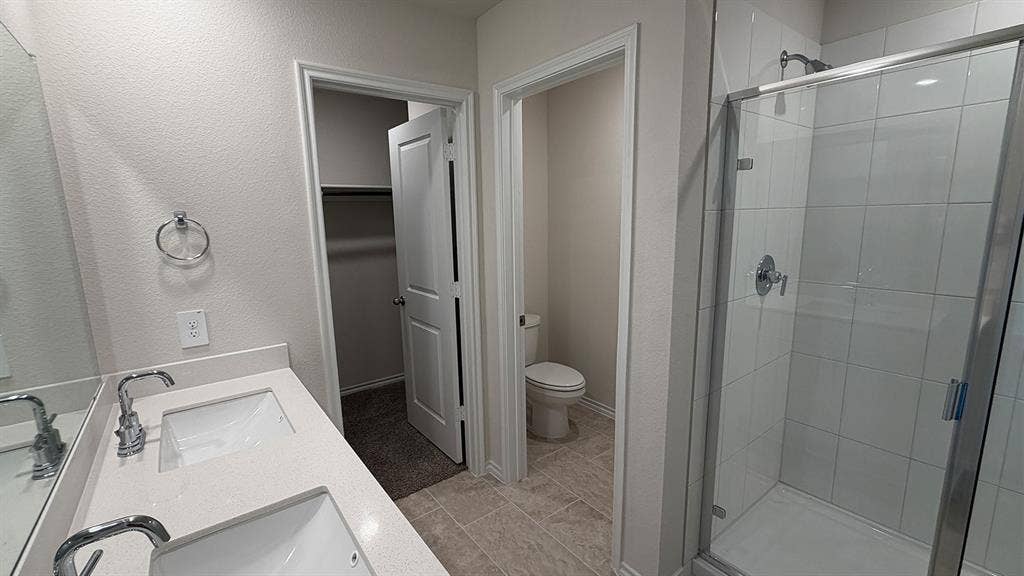 3013 Hidden Valley Drive, Lindale, TX 75771 Dual vanity with undermount sinks and chrome fixtures, framed by a large wall mirror
