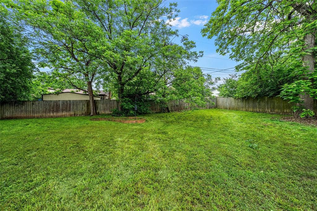 3301 Loma Vista Drive, Waco, TX 76708 Expansive fenced backyard featuring a manicured lawn and mature trees providing natural shade