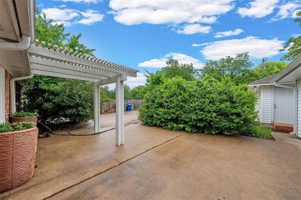 3301 Loma Vista Drive, Waco, TX 76708 Expansive concrete patio featuring a white pergola structure and surrounding mature greenery