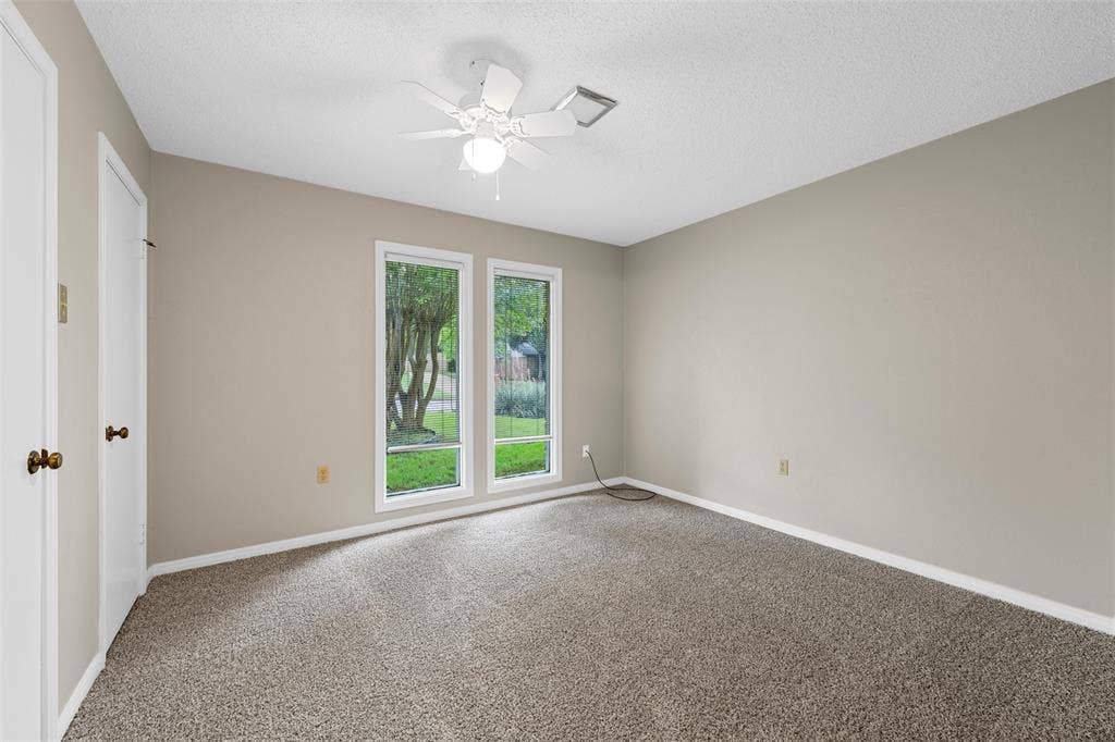 3301 Loma Vista Drive, Waco, TX 76708 Carpeted room featuring two white-framed windows, a ceiling fan with integrated lighting, and neutral wall tones