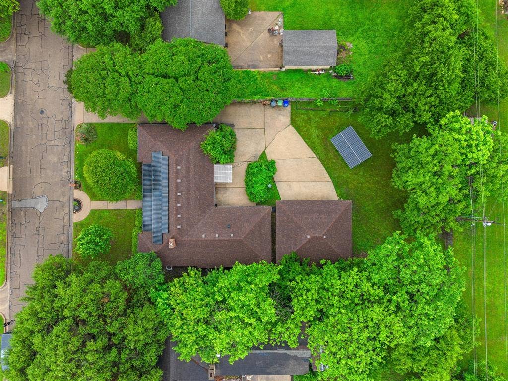 3301 Loma Vista Drive, Waco, TX 76708 Property featuring a brown shingle roof, extensive solar panel installation, a concrete driveway, and mature landscaping
