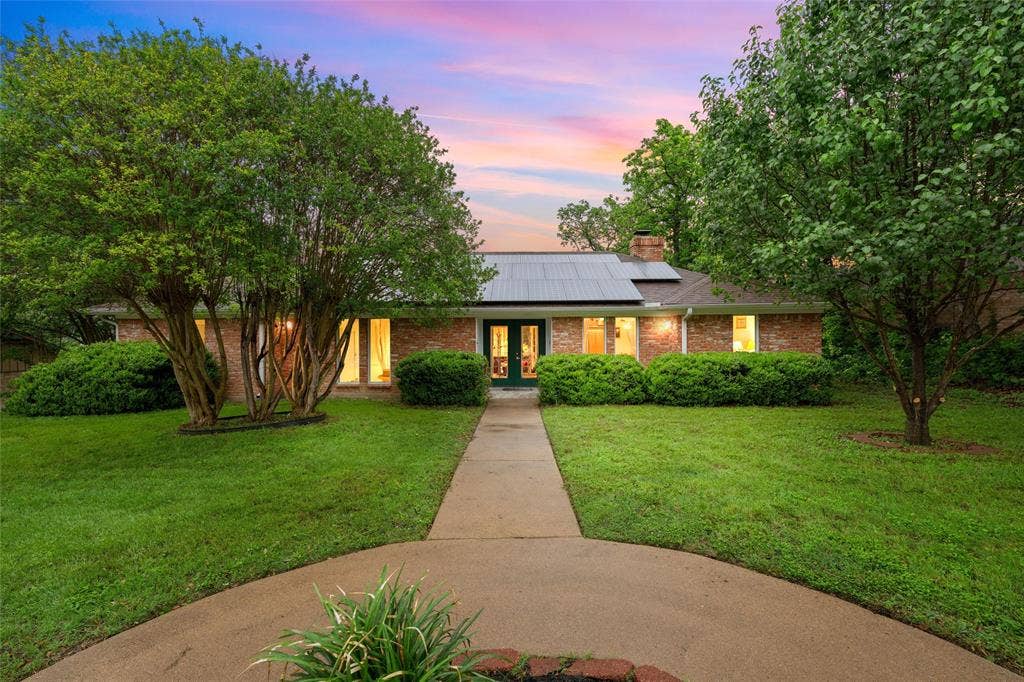 3301 Loma Vista Drive, Waco, TX 76708 Brick facade residence featuring solar panels, a central entryway, and a concrete pathway