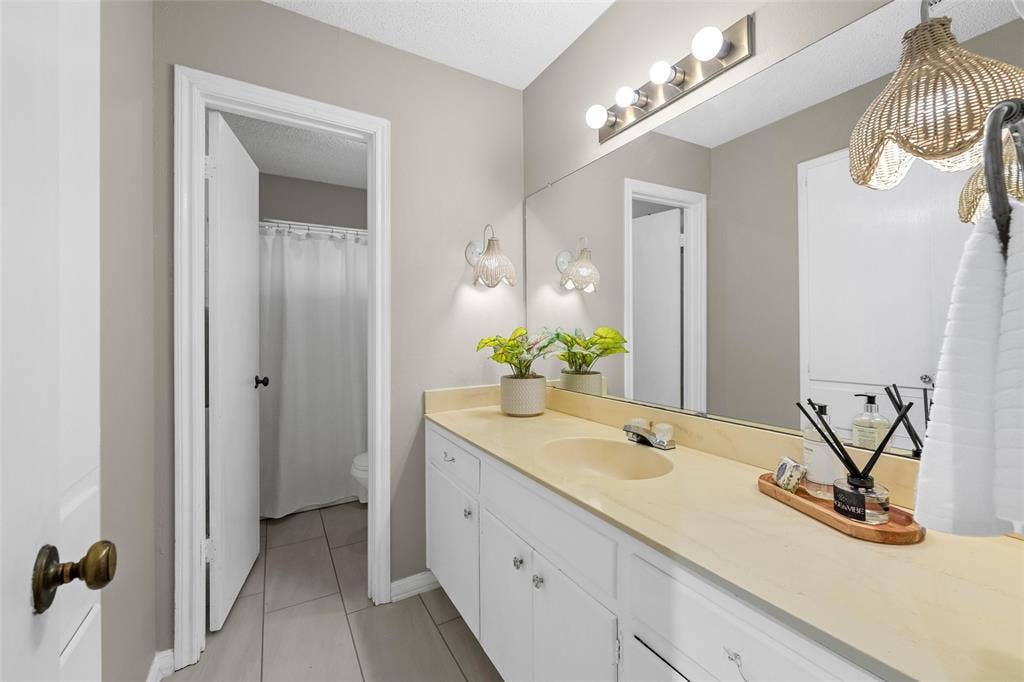 3301 Loma Vista Drive, Waco, TX 76708 Full-width vanity featuring a single sink and extensive countertop space, complemented by a large mirror and overhead four-bulb light fixture