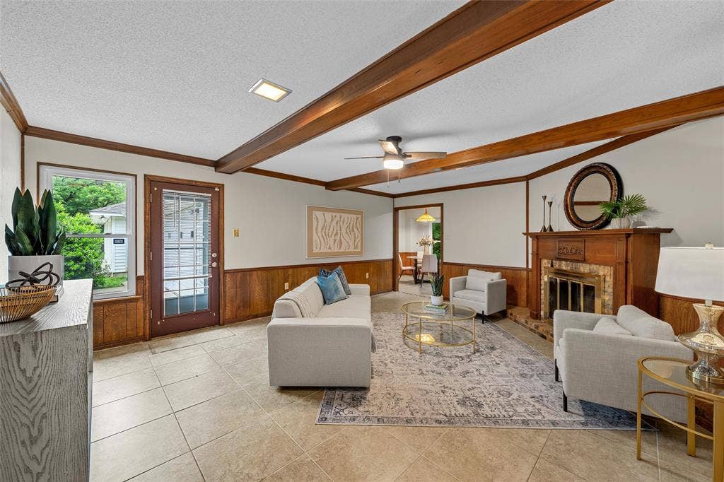 3301 Loma Vista Drive, Waco, TX 76708 Living area featuring exposed wood beams, tile flooring, wood paneling, a fireplace with a wood mantle, and a ceiling fan