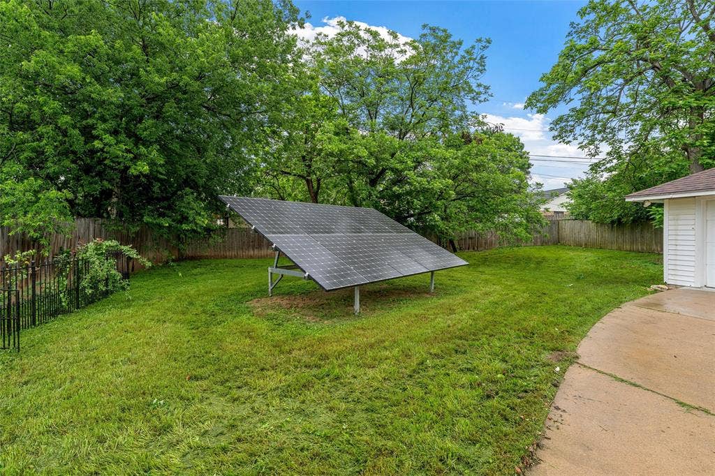 3301 Loma Vista Drive, Waco, TX 76708 Expansive backyard featuring a ground-mounted solar panel array, a concrete patio, and mature trees providing natural screening