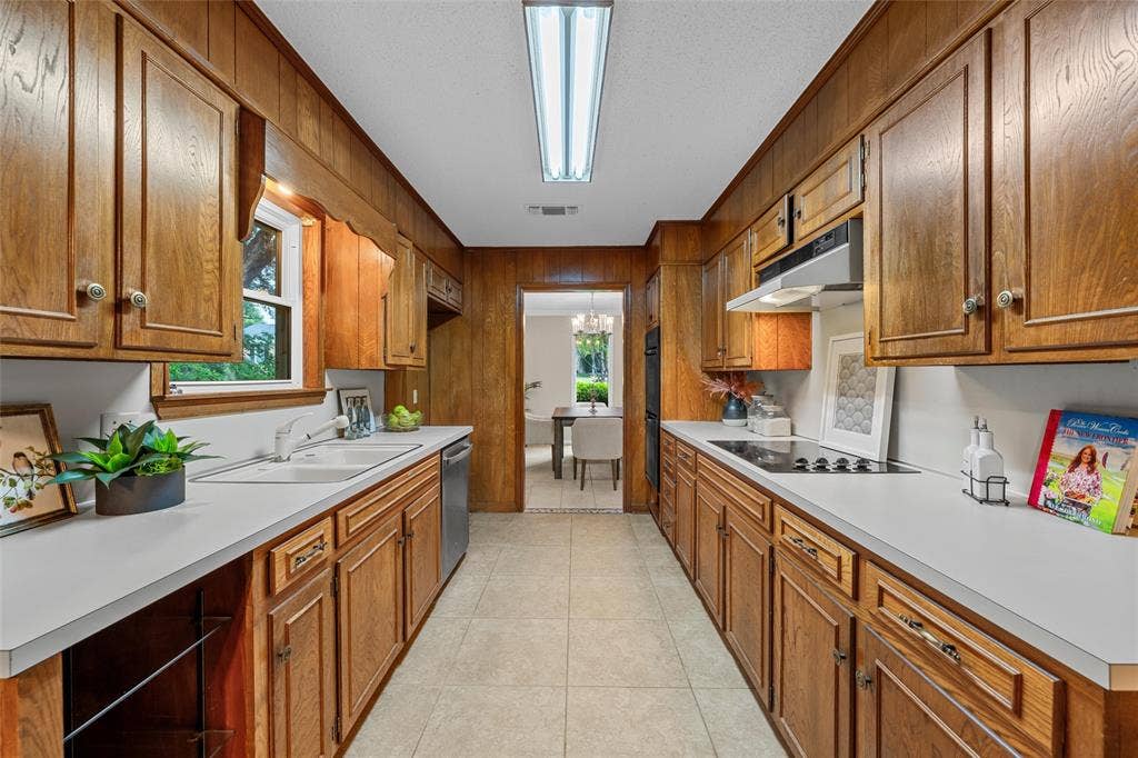 3301 Loma Vista Drive, Waco, TX 76708 Galley kitchen featuring extensive wood-finish cabinetry, solid surface countertops, a built-in electric cooktop, double wall ovens, and a recessed ceiling light fixture