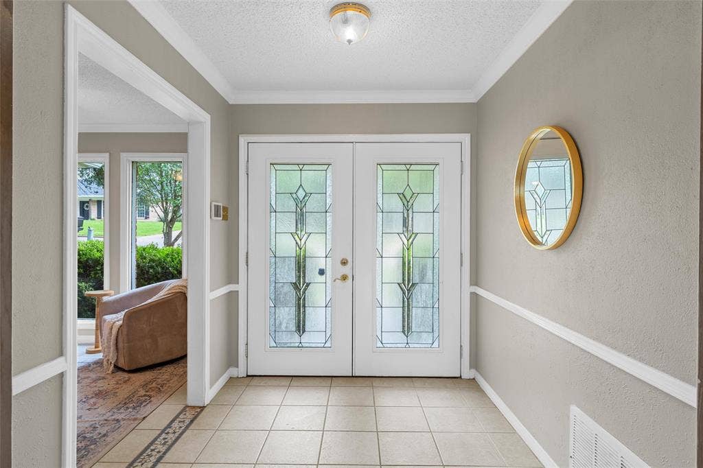 3301 Loma Vista Drive, Waco, TX 76708 Entryway featuring double doors with decorative glass panels, neutral wall tones, white crown molding, and tiled flooring with an accent border