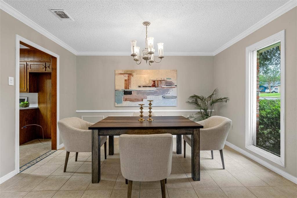 3301 Loma Vista Drive, Waco, TX 76708 Formal dining area featuring neutral wall paint, crown molding, chair rail molding, a chandelier, and tile flooring