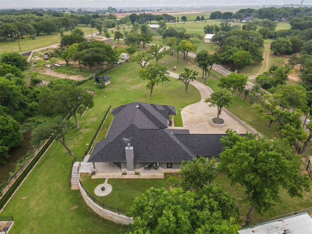 2100 Gene Court, Granbury, TX 76048 Expansive property featuring a contemporary residence with a dark shingle roof and a prominent chimney