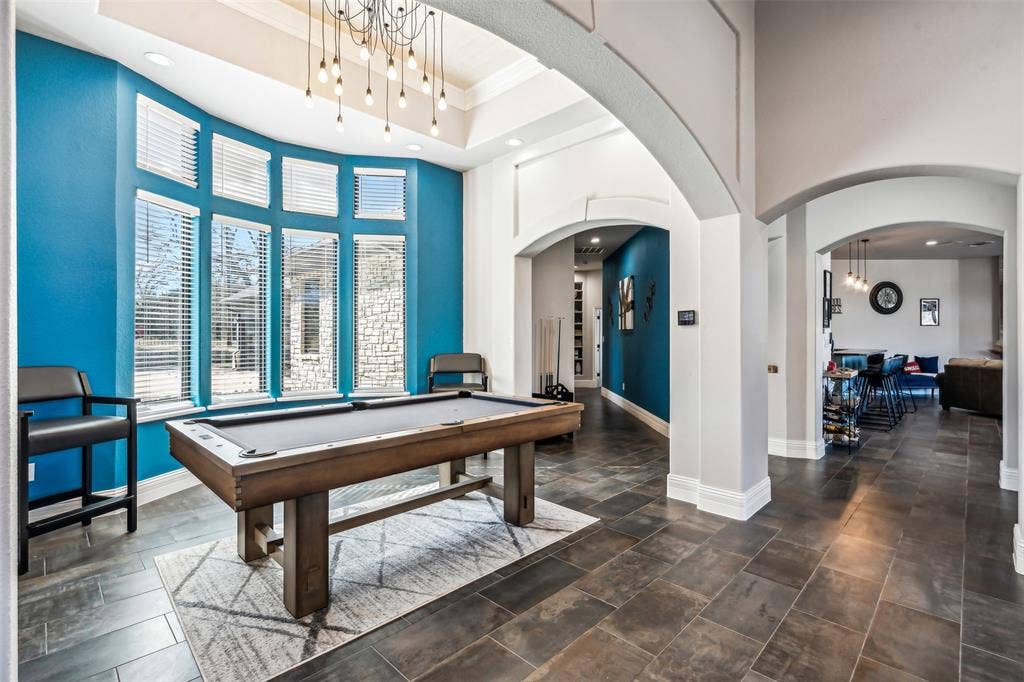 2100 Gene Court, Granbury, TX 76048 Spacious entertainment area featuring a curved bay window, modern chandelier, dark tile flooring, and arched doorways