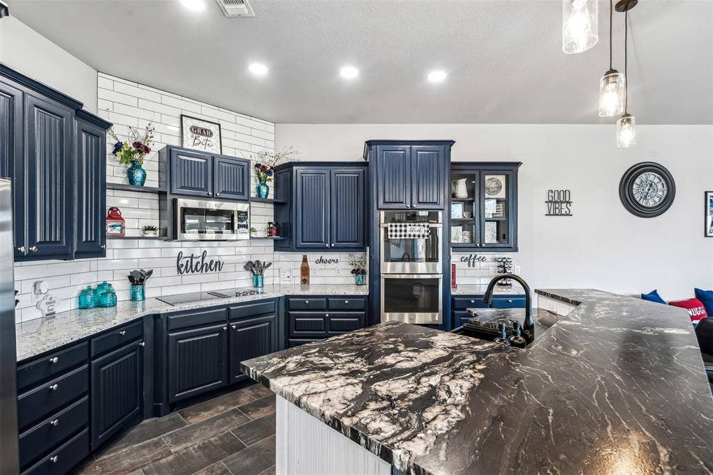 2100 Gene Court, Granbury, TX 76048 Spacious kitchen featuring dark cabinetry, two-tone countertops, a subway tile backsplash, and built-in stainless steel appliances