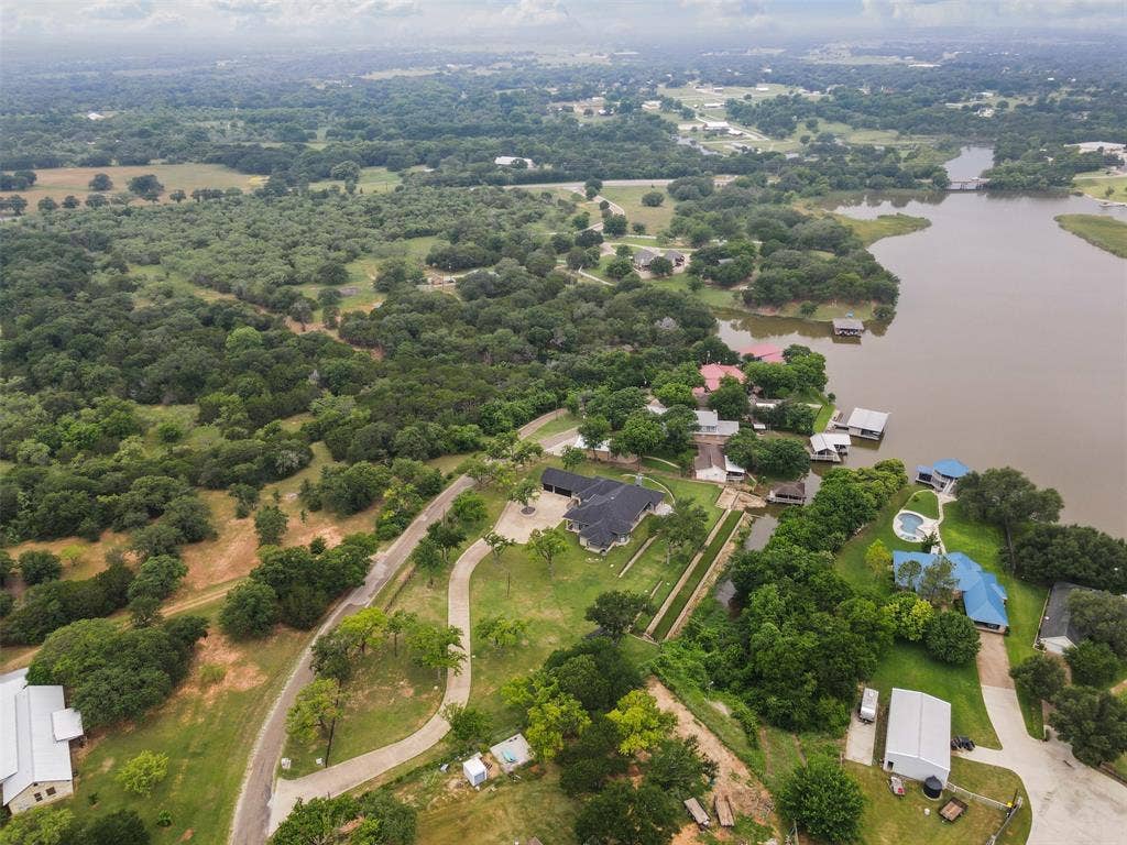 2100 Gene Court, Granbury, TX 76048 Expansive waterfront property featuring a large residence with a dark roof, private boat slips, and multiple outbuildings